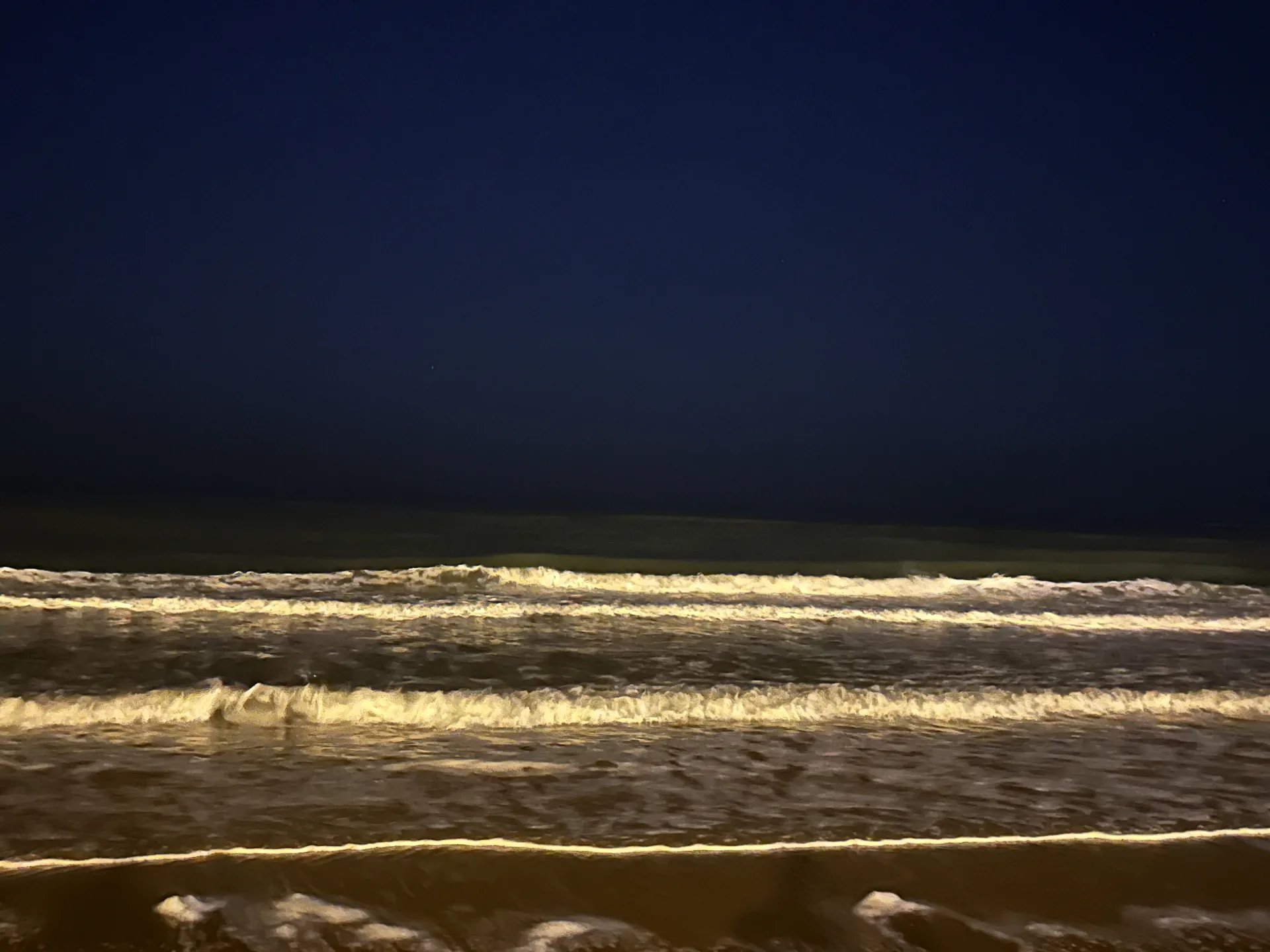 夜色中的海浪被岸边灯光照亮 / Waves lit by shore lights at night
