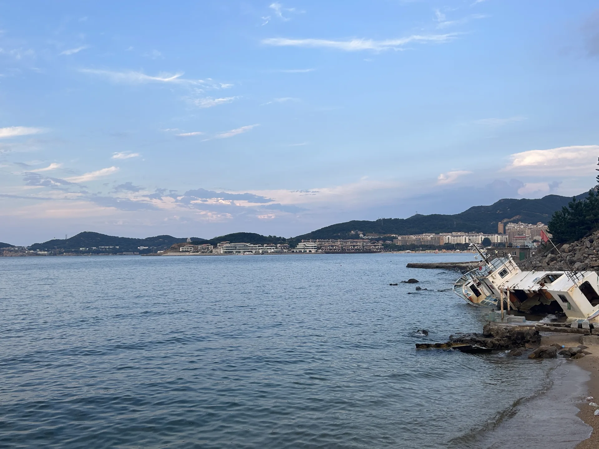 蓝色海湾岸边停着一艘倾斜的船 / A tilted boat resting on the shore of a blue bay