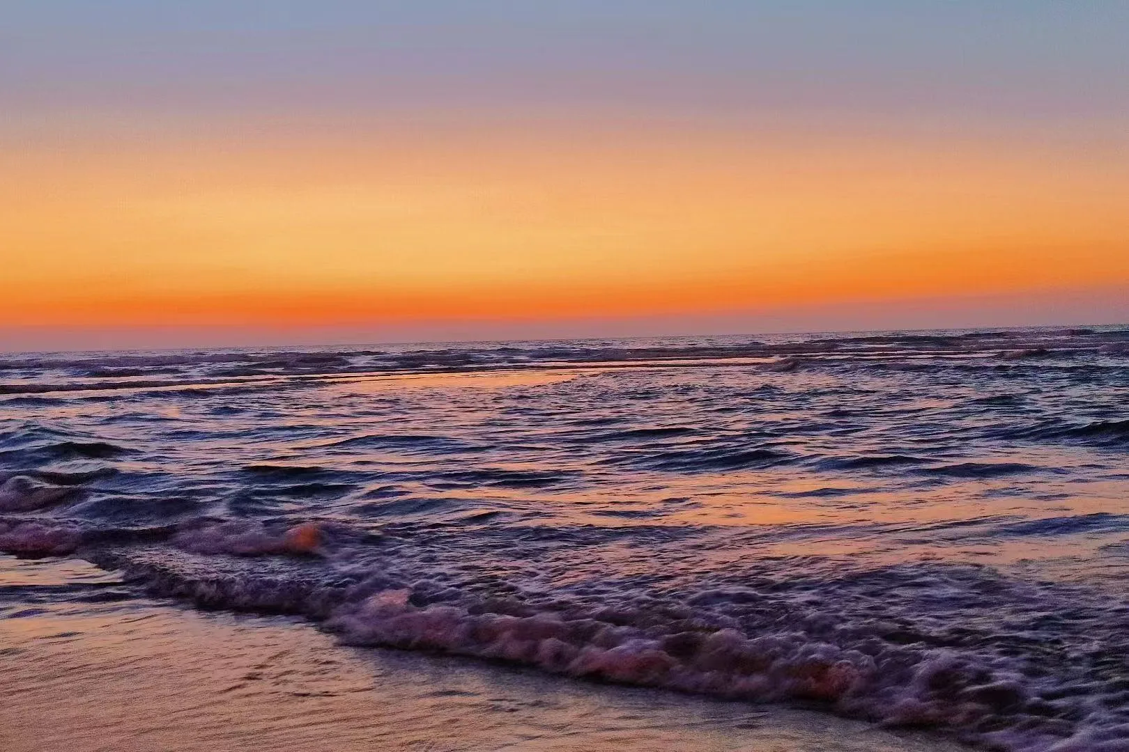 橙紫色晚霞映照着海面与近岸浪花 / Orange and violet dusk over the sea and nearshore waves