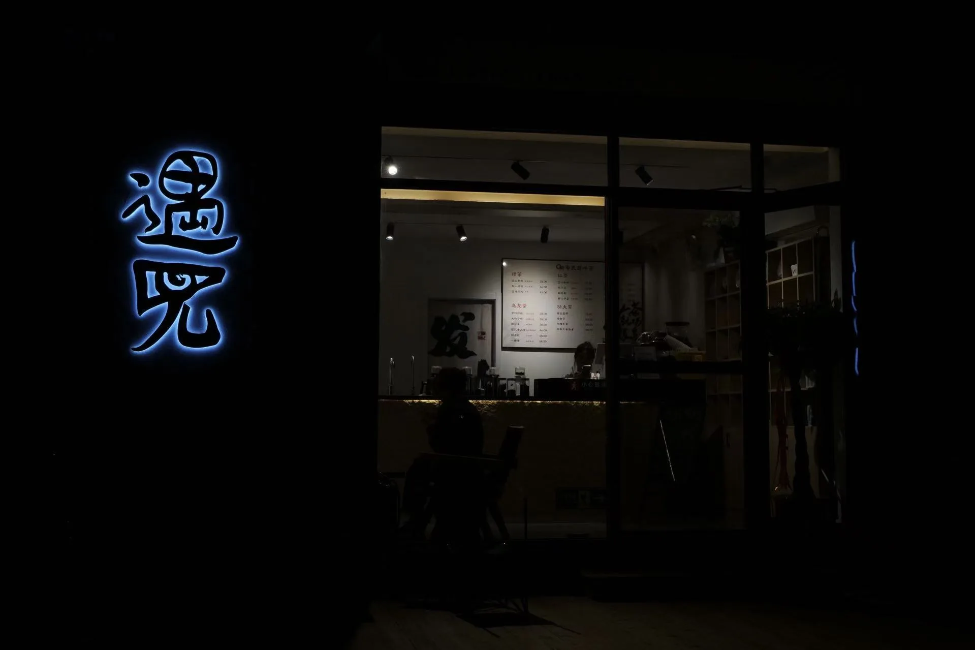 夜色中发光的遇见招牌与临街茶店 / A glowing Encounter sign and street-facing tea shop at night